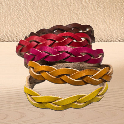 Braided leather bracelets in red, pink, tan, dark brown and yellow on a beige surface. Handmade braided leather bracelet crafted from vegetable tanned cowhide.
